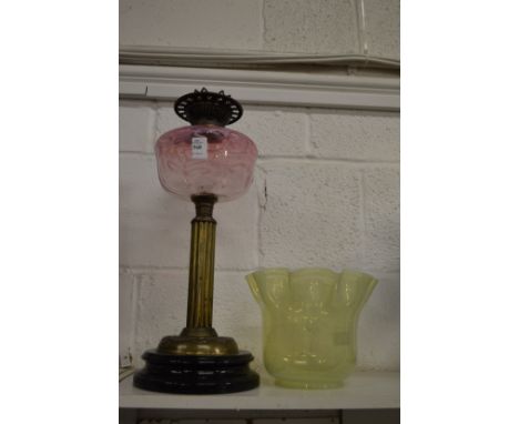 A Victorian brass oil lamp with pink glass reservoir and Vaseline glass shade.