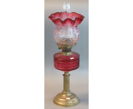 Early 20th century double oil burner lamp having cranberry and clear glass shade above a cranberry glass reservoir standing o