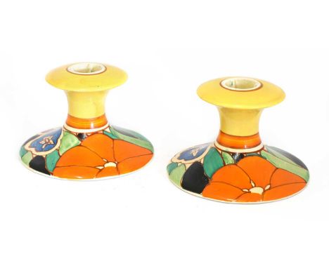A pair of Clarice Cliff 'Red Gardenia' candlesticks, 1930s, each of waisted form with a flared sconce and base, printed with 
