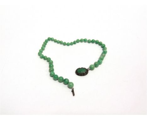 A JADE BEAD NECKLACE  the forty one graduated beads of approximately  9-5mm diameter, to a filigree carved jade set clasp, 33