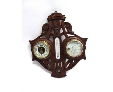 AN EDWARDIAN BAROMETER/THERMOMETER/HYGROMETER  mounted on a carved oak frame, 32cm wide 36cm high