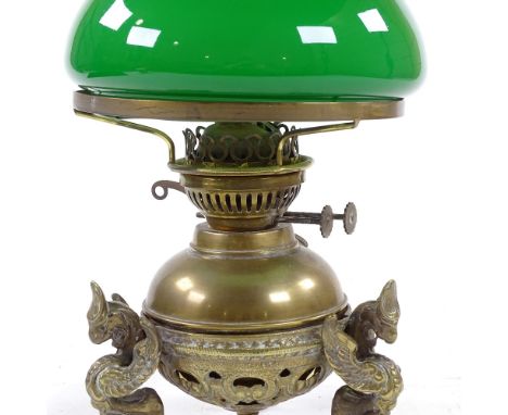 A brass oil lamp on cast griffon feet, with green glass shade, height 35cm 