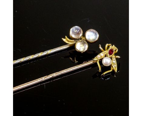2 early 20th century unmarked gold stone set stickpins, comprising ruby and pearl bug example, and cabochon moonstone 3-leaf 