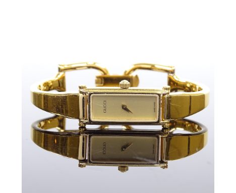 GUCCI - a lady's gold plated stainless steel 1500 quartz bangle wristwatch, brushed gold face with rectangular case, serial n