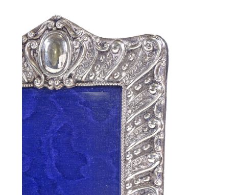 A Victorian silver-fronted strut photo frame, relief embossed leaf and foliate decoration with blue velvet backing, by Henry 