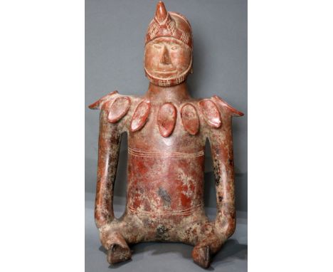 A Pre-Columbian Colima, West Mexico, seated shaman, 200BC-300AD, wearing an incised helmet, above a shell decorated neckline,