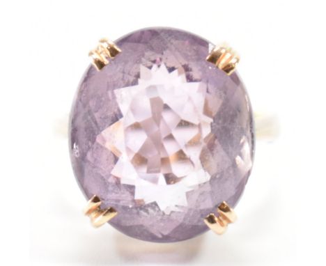 A vintage 9ct gold and amethyst dress ring. The ring being set with a oval cut amethyst in a basket setting with pinched shou