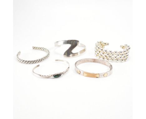 A group of five silver bangles. The lot to include an open rope twist bangle (marked 925), a ball design lattice work bangle 