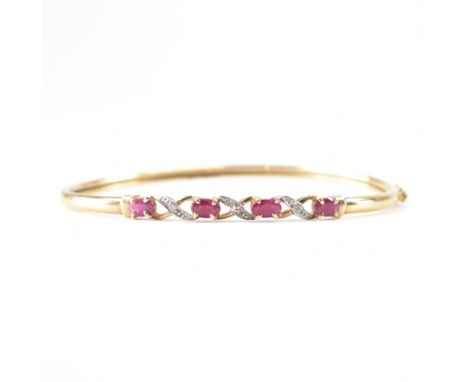 A vintage gold ruby and diamond bangle bracelet. The bracelet being set with four oval cut rubies and diamond accent stones. 