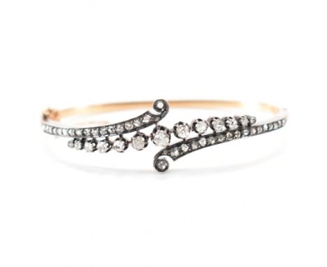 A French Belle Epoque diamond bangle. The hinged bangle having an old cut diamond swirl head of old cut diamonds to a gold ba