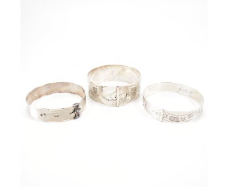 A group of three silver bangle bracelets. The lot to include three buckle bangles with engraved foliate and star detailing an