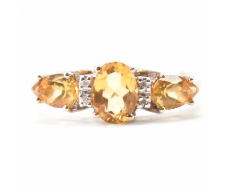 A hallmarked 9ct gold citrine and diamond ring. The ring being set with a central oval cut citrine flanked by two pear cut ci