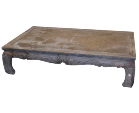 A Chinese elm and rattan food table, of rectangular section, with a dragon and foliate carved frieze, raised on scroll legs, 