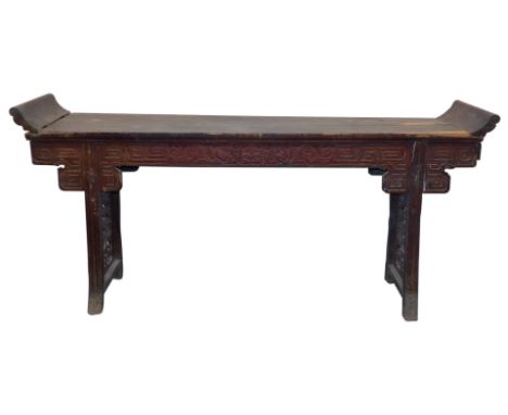 A Chinese hardwood altar table, the scroll ended top above a carved frieze, raised on trestle supports, with inset fretwork p