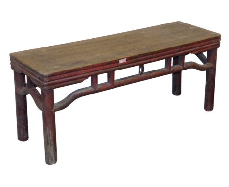 A Chinese red lacquered bench, of rectangular section, with a carved frieze, raised on cylindrical legs, 44cm high, 105cm wid