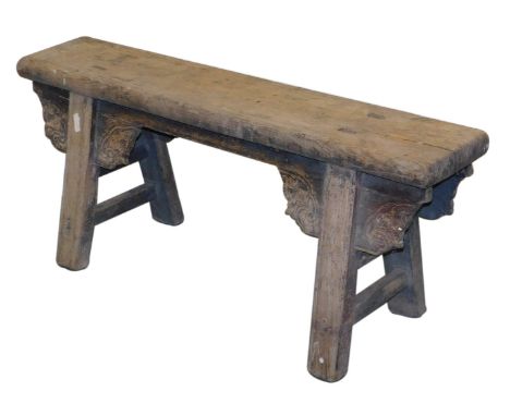 A Chinese wooden bench, raised on trestle end supports, with foliate carved brackets, united by stretchers, 107cm wide.