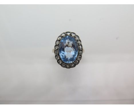 An 18ct and white continental metal ring, the central stone approx 14mm x 10mm x 6mm surrounded by small diamonds, ring size 