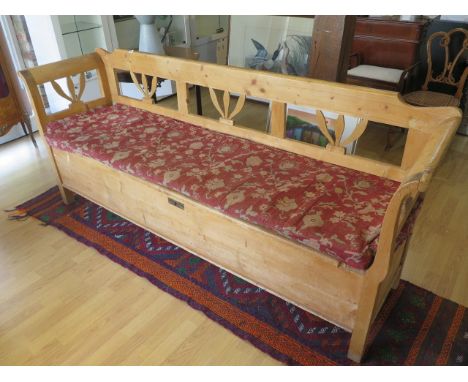 A 19th century continental stripped pine hall bench with lift upseat and cushion, 90cm tall x 210cm x 56cm 