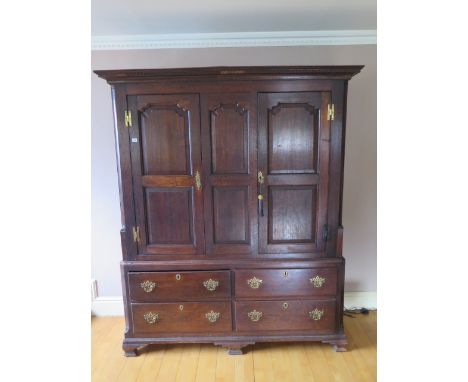 An 18th century oak  cupboard on chest with two panelled doors above four drawers on shaped bracket feet, some losses to frie