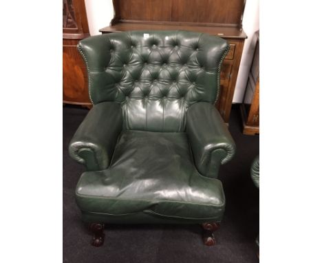A large leather green button back armchair resting on ball and claw feet to front with metal studding to edges.