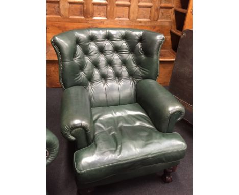 A large leather green button back armchair resting on ball and claw feet to front with metal studding to edges.