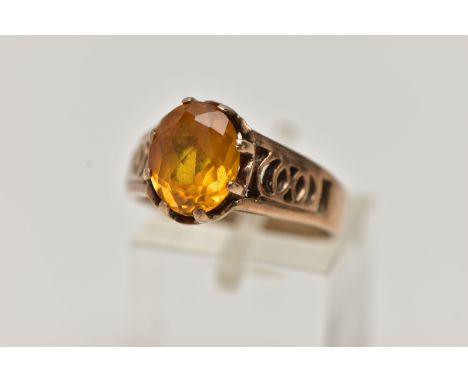 A 9CT GOLD GEMSTONE RING, designed with a six claw set, oval cut orange stone assessed as sapphire, to the openwork detailed 