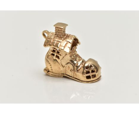 A 9CT GOLD CHARM, yellow gold charm of a boot house, fitted with a hinged sole, opens to reveal children playing with enamel 