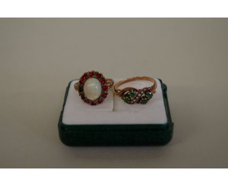 An unmarked gold opal and garnet cluster ring; together with an emerald and seed pearl example. (2) 