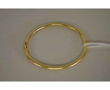 A gold hinged bangle stamped 750, 7.9g. 