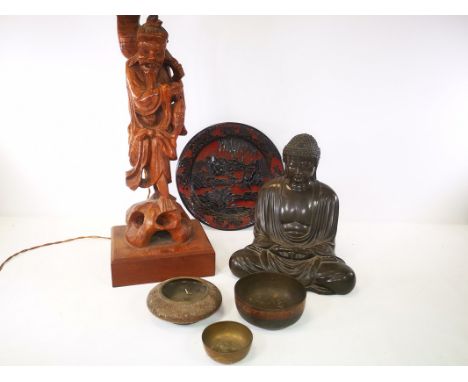 A carved wooden table lamp in the form of an eastern fisherman, together with a cast metal Buddha figure, three oriental bras