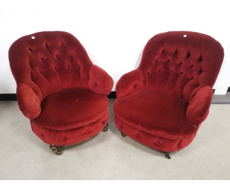 Pair of low button back arm chairs, finished in a deep red farbric, raised on turned supports and castors. (2) 