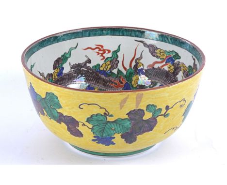 A large Asian ceramic bowl,   the exterior glazed in yellow and decorated with scrolling vines, the interior glazed in white 