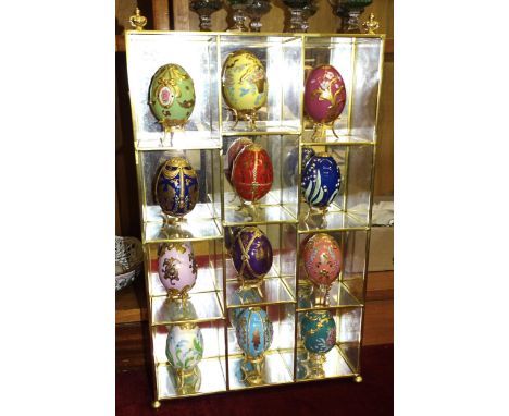 Twelve Franklin Mint Fabergé eggs decorated with enamelled, gilt and jewelled flowers, on gilt stands, together with a displa