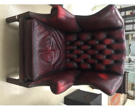 A burgundy leather button back wingback chair