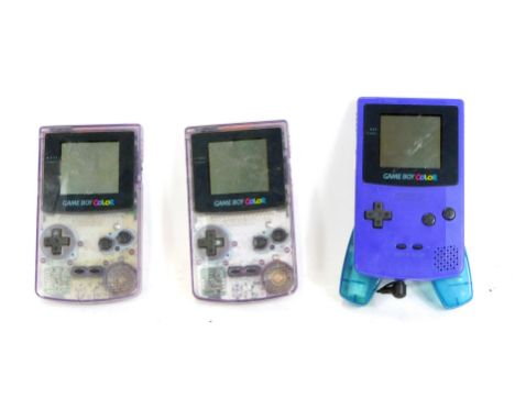 Three games consoles, comprising two Gameboy Colours, in clear casing, and a Gameboy Colour, in dark blue casing with additio