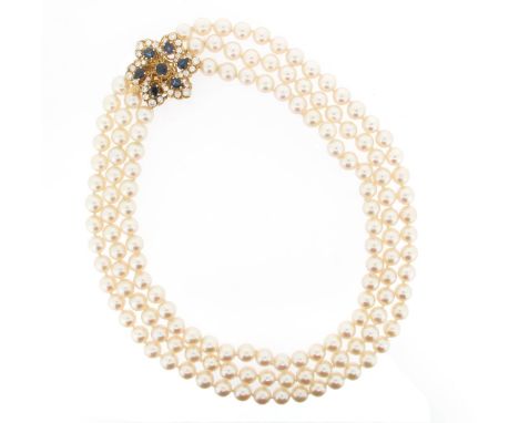 A three row cultured pearl necklace, with a sapphire and diamond flower-head clasp. 49cm long.