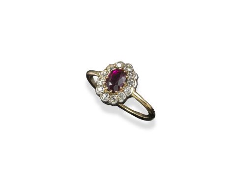 A ruby and diamond cluster ring, the oval-shaped ruby is millegrain-set within a surround of old circular-cut diamonds in pla