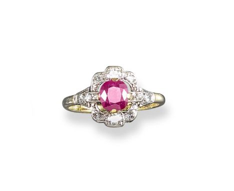 A ruby and diamond cluster ring, the oval-shaped ruby is set within an openwork surround of graduated circular-cut diamonds i