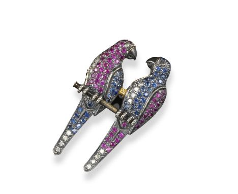 A gem-set double parrot brooch, the two birds sitting on a perch and looking at each other. Pavé-set with circular-cut rubies