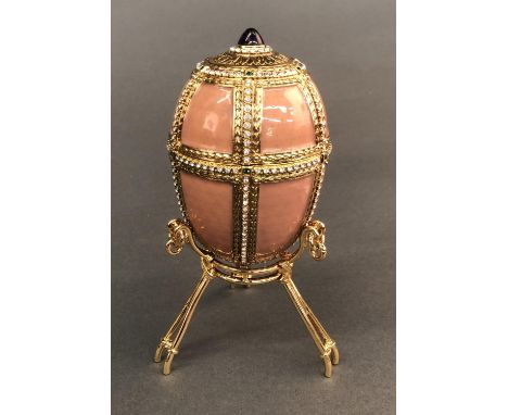 A Faberge Danish palace egg. Pink egg studded with crystals that opens on a hinge. Inside is an accordion style picture frame