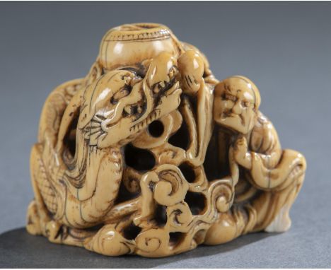 An ivory netsuke of Rakan and dragon emerging from bowl. Mid 18th century. Unsigned. 2 3/4" x 2 1/4" x 1 1/4".Condition: Chip