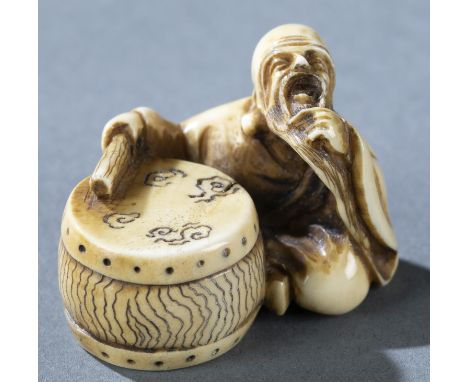 A marine ivory netsuke of an old man seated next to a drum. Mid 19th century. Signed on underside of drum. H: 2.95cm.Conditio