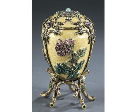 A Jay Strongwater enameled decorative egg on stand. Pale yellow enamel decorated with flowers and rhinestones Raised on ename