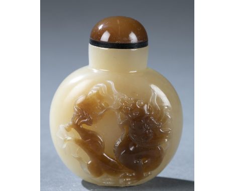 A Chinese agate snuff bottle. Late 19th century. Light tan agate with dark brown inclusion on front face carved to depict a d