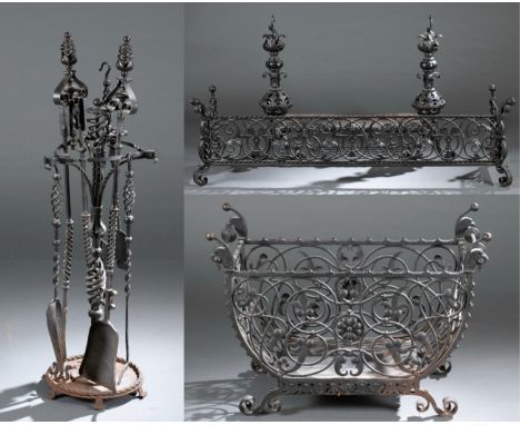 A Baroque style iron fireplace set. 20th century. Includes log basket, fender, andirons, and fire tool set. Wrought and cast 