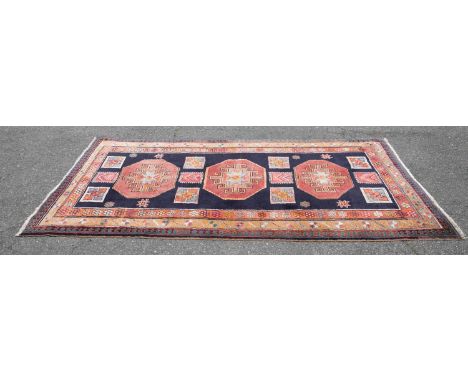 A Persian Ardabil wool rug. 20th century. Hand-knotted wool. Three repeating central medallions on navy ground surrounded by 