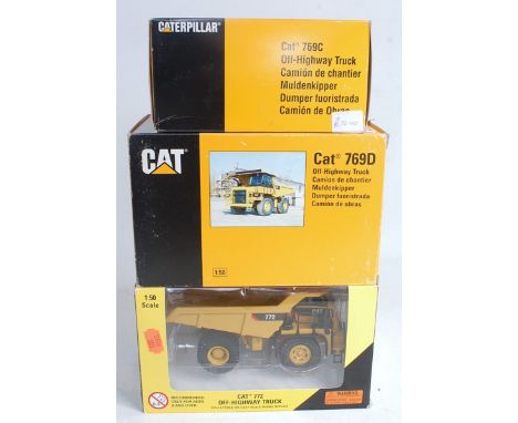 A Cat 769D off-highway truck, 1/50 scale; a Cat 772 off-highway truck, 1/50 scale, in window box; and a Cat 769C off-highway 