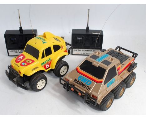 Two loose working Nikko remote control cars with hand units to include the Nikko Mammoth 1/18 scale combat 6WD Tronico togeth