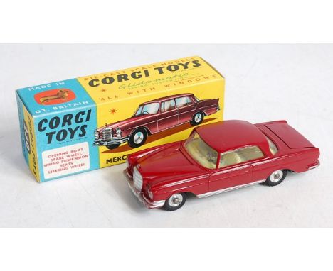 A Corgi Toys No. 230 Mercedes Benz 220 SE coupe comprising maroon body with yellow interior and spun hubs in the original blu