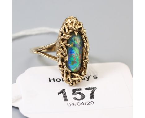 A single stone opal ring, the oval opal claw mounted within abstract wirework mount, to plain bifurcated shank Ring size M, 7